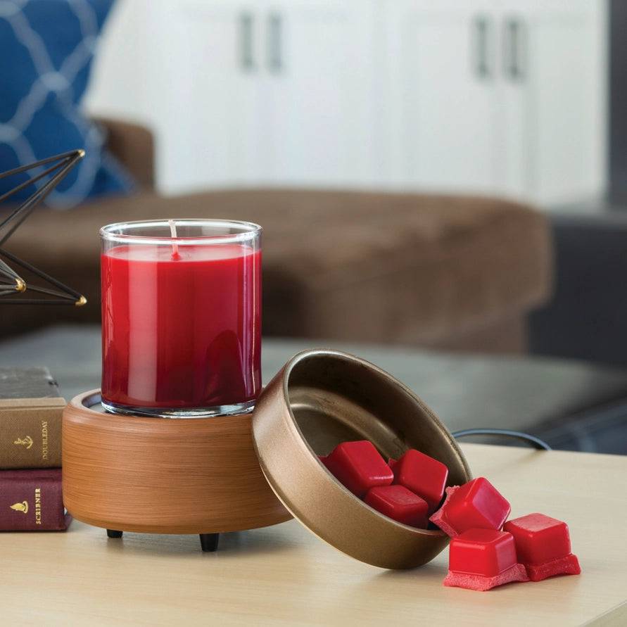 Red candle in a glass holder with a wooden container holding wax cubes on a table.