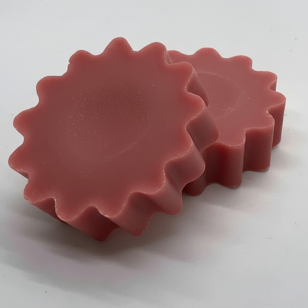 Two rose pink, scalloped-edge wax melts stacked on a plain white surface.