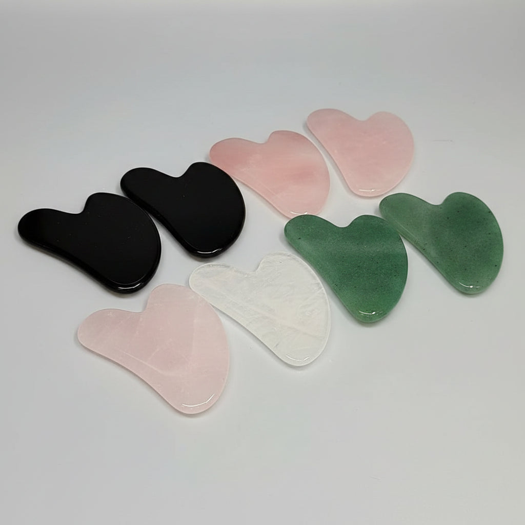 Set of gua sha tools in various colors on a white background