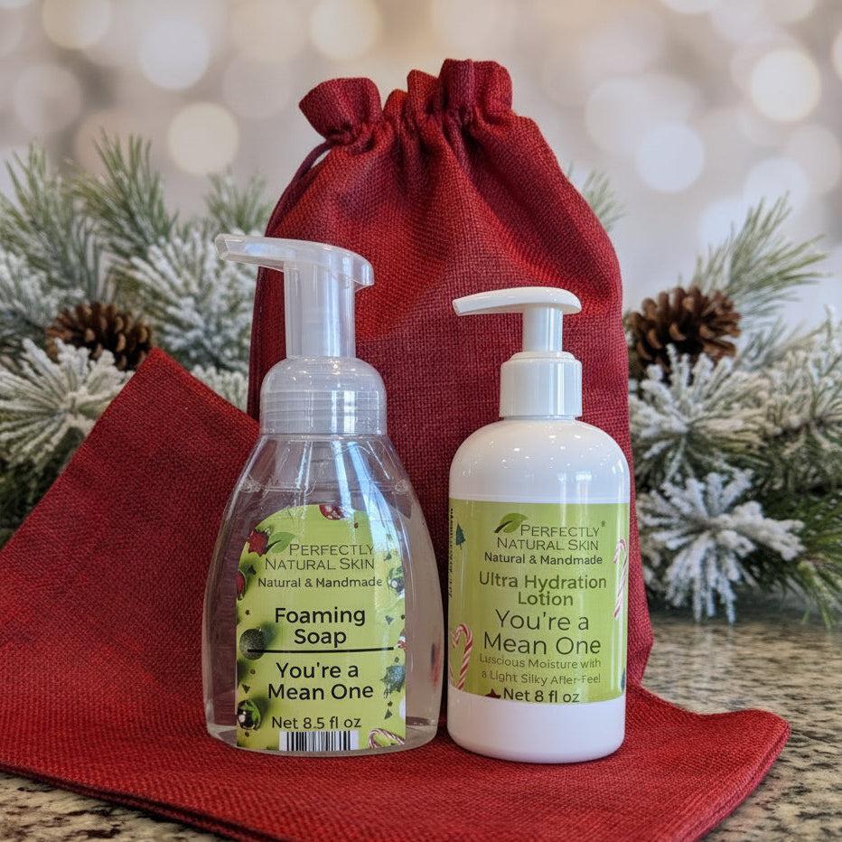 Two bottles of 'Perfectly Natural Skin' products on a red cloth with Christmas decorations in the background.