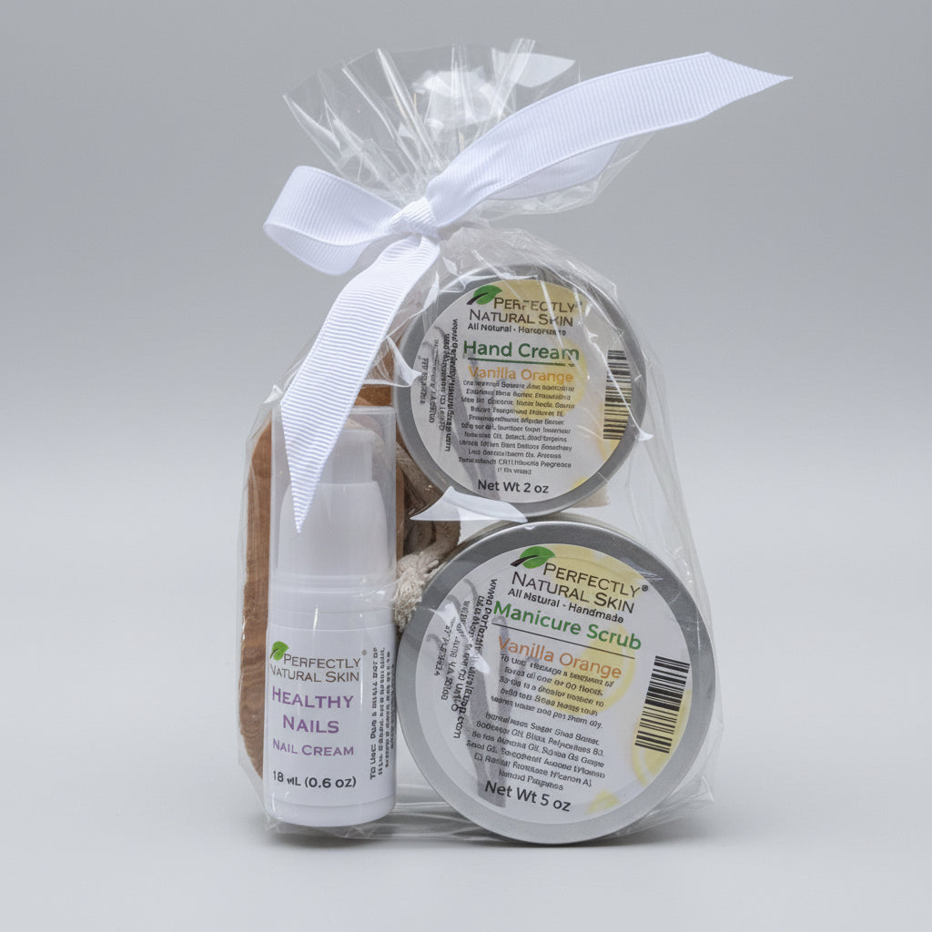 Three small natural skincare products arranged on a white surface: a wrapped hand cream in clear cellophane with a white ribbon, a round body scrub jar labeled Manicure Scrub, and a small clear bottle labeled Healthy Skin Cream.